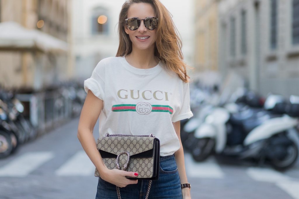 FLORENCE, ITALY - JANUARY 11: German fashion blogger and model Alexandra Lapp is wearing retro vibe Gucci printed cotton T-shirt, featuring a throwback Gucci logo, this piece features distressed detailing around the neckline, slim fit Wedgie Icon Fit Jeans from Levi’s, suede /buckskin leather trench coat from Oui, Dionysus GG Supreme Medium Gucci shoulder bag, Le Specs sunglasses, red pumps from Gianvito Rossi on January 11, 2017 in Florence, Italy. (Photo by Christian Vierig/Getty Images) *** Local Caption *** Alexandra Lapp