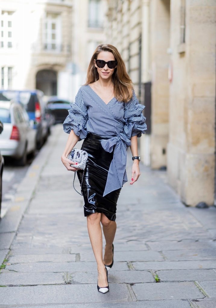 PARIS; FRANCE; Model and Blogger Alexandra Lapp wearing latex skirt and ruched sleeve top, a black Couture Latex Crystal pencil Skirt from Atsuko Kudo, Pepita blouse top from Storets with black and white check print, Decollete neckline and riches sleeve Black and white pumps from Saint Laurent, Oversized Audrey sunglasses from Celine, Black and white 2.55 bag in tweed from Chanel on March 3, 2017 in Paris, France.