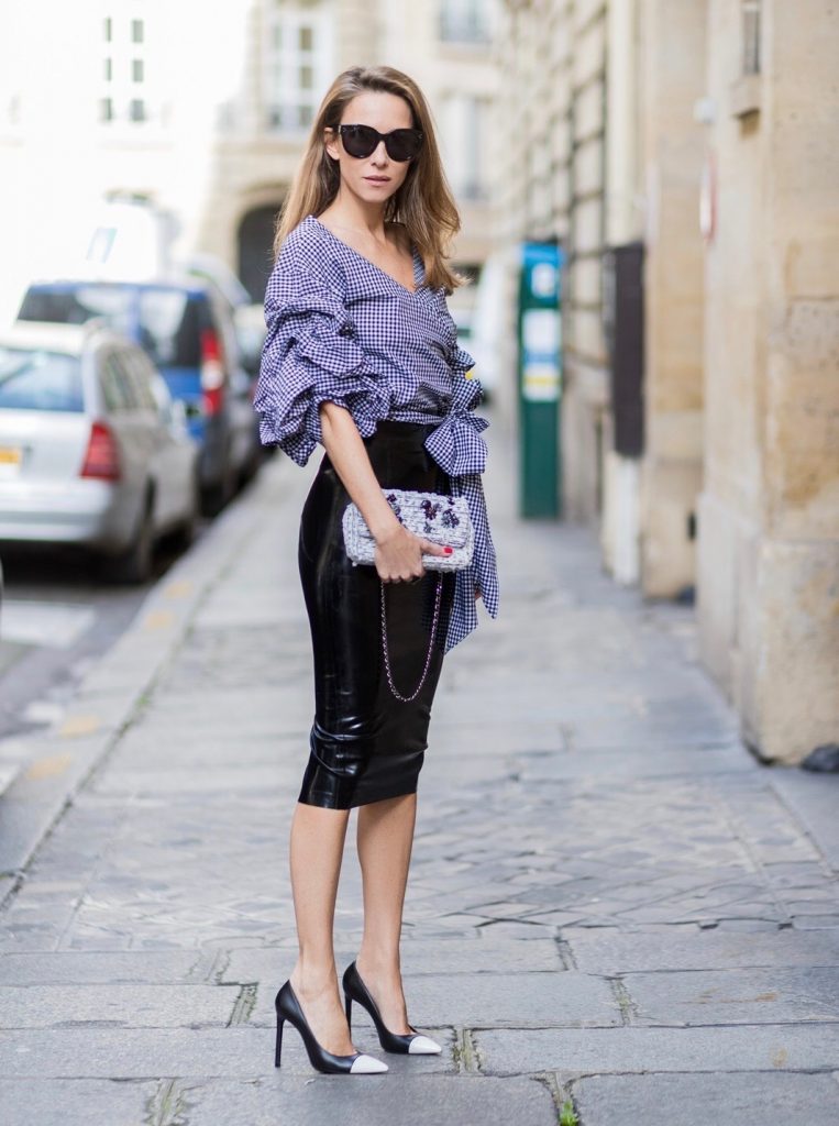 PARIS; FRANCE; Model and Blogger Alexandra Lapp wearing latex skirt and ruched sleeve top, a black Couture Latex Crystal pencil Skirt from Atsuko Kudo, Pepita blouse top from Storets with black and white check print, Decollete neckline and riches sleeve Black and white pumps from Saint Laurent, Oversized Audrey sunglasses from Celine, Black and white 2.55 bag in tweed from Chanel on March 3, 2017 in Paris, France.