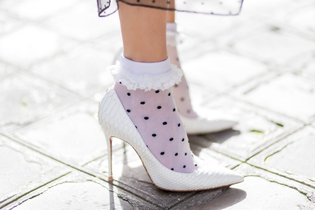 PARIS; FRANCE; Blogger and Model Alexandra Lapp rock dots by wearing knit Oui Black Lace Layer Skirt from Storets with layers of differently patterned sheer fabrics, a classic skater style silhouette with lace and dotted patterns cascading down below the leg, Leather waist belt - Set Fashion, Socks - vintage, Pumps - white snake pumps from Christan Louboutin, Sunglasses - Celine Audrey, Clutch - Chanel on March 3, 2017 in Paris, France.