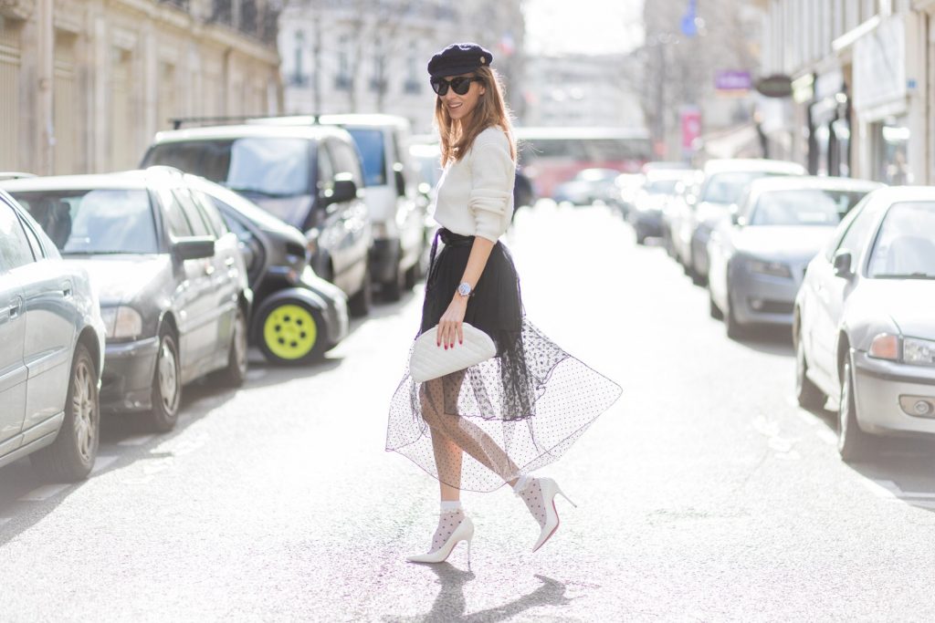 PARIS; FRANCE; Blogger and Model Alexandra Lapp rock dots by wearing knit Oui Black Lace Layer Skirt from Storets with layers of differently patterned sheer fabrics, a classic skater style silhouette with lace and dotted patterns cascading down below the leg, Leather waist belt - Set Fashion, Socks - vintage, Pumps - white snake pumps from Christan Louboutin, Sunglasses - Celine Audrey, Clutch - Chanel on March 3, 2017 in Paris, France.