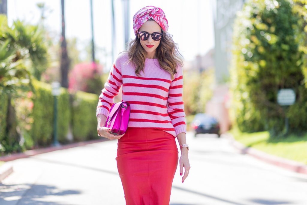 Model and fashion blogger Alexandra Lapp wearing a scarf as a bandana from Heartbreaker, a red stretch leather pencil skirt from American Retro, pink and red striped cashmere pullover by Heartbreaker, red lacquer pumps from Gianvito Rossi, an electric-pink Patricia bag, a small crossbody in vachetta leather, complete with a well-organized interior lined in orange sueded nylon, sunglasses from Le Specs, IWC Da Vinci Automatic 36 watch in 18-carat red gold with diamonds and jewelry from AYS (Art Youth Society) on April 20, 2017 in Los Angeles, California.
