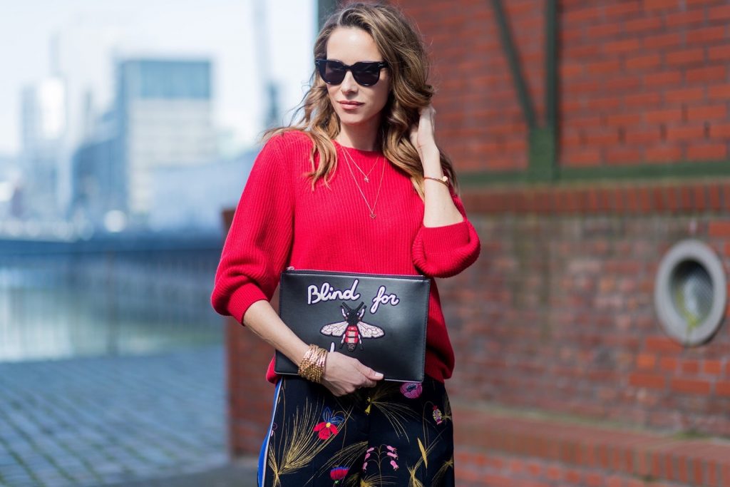Model and fashion blogger Alexandra Lapp wearing marlene pants, a black and multicoloured floral print trousers from Fendi featuring a high rise, a concealed front fastening, side pockets, applique stripes at the sides, creases and a wide leg, red cashmere knitwear by Valentino, black suede So Kate pumps from Christian Louboutin, gold plated cuff from Gas Bijoux, Celine sunglasses and a black leather ring detail continental purse bag or wallet from Fendi featuring an embossed logo, a press stud fastening, multiple interior card slots, an interior zipped compartment and a gold-tone chain shoulder strap. on March 30, 2017 in Duesseldorf, Germany.