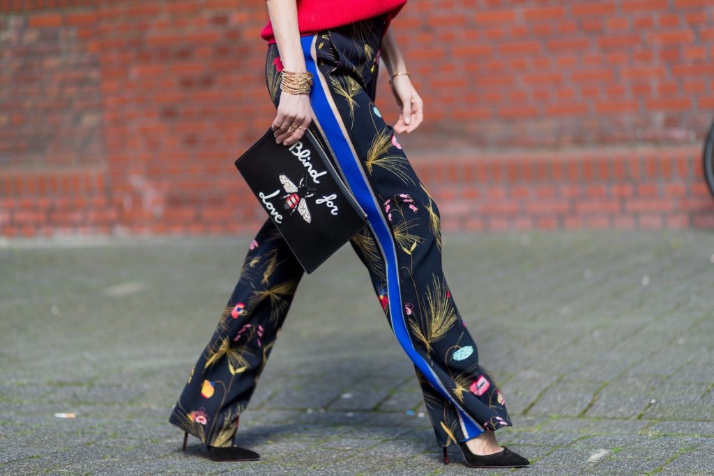 Model and fashion blogger Alexandra Lapp wearing marlene pants, a black and multicoloured floral print trousers from Fendi featuring a high rise, a concealed front fastening, side pockets, applique stripes at the sides, creases and a wide leg, red cashmere knitwear by Valentino, black suede So Kate pumps from Christian Louboutin, gold plated cuff from Gas Bijoux, Celine sunglasses and a black leather ring detail continental purse bag or wallet from Fendi featuring an embossed logo, a press stud fastening, multiple interior card slots, an interior zipped compartment and a gold-tone chain shoulder strap. on March 30, 2017 in Duesseldorf, Germany.