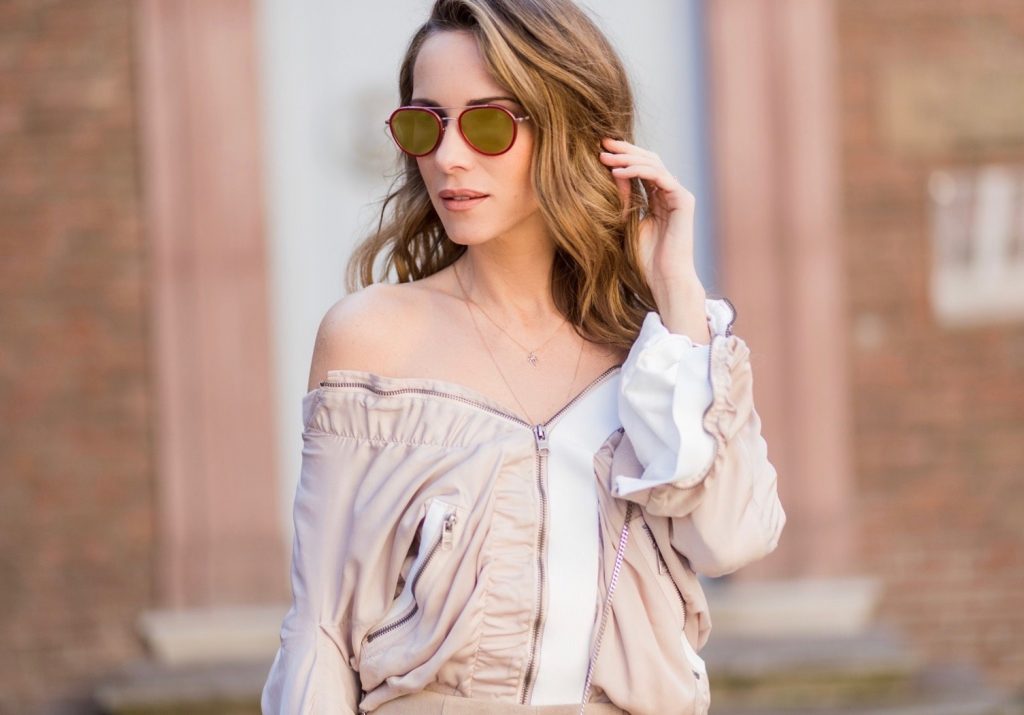 Model and fashion blogger Alexandra Lapp wearing the color powder, a bomber jacket by Tigha which has a slightly shimmering fabric with feminine ruffled parts and sporty elastic pipes and zip details to create an urban look,leather skirt in beige from Steffen Schraut, sandals made of linen with a rose application, sunglasses from Thom Browne, filigree rose gold jewelry from Art Youth Society and a studded embellished crossbody bag from Fendi featuring a foldover top with magnetic closure, an interior zipped compartment, multiple interior card slots and a silver-tone chain shoulder strap on March 30, 2017 in Duesseldorf, Germany.