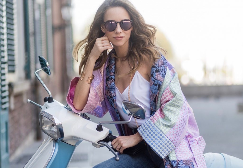 Model and fashion blogger Alexandra Lapp wearing a printed kimono / panel robe from Natasha Zinko, slim fit high waist Jeans from Rag & Bone, Mules by Gucci with open-toe-silhouette in glittery silver grey, white silk tank top from Jadicted, colorful mirrored sunglasses from Les Specs, black leather ring detail continental purse bag from Fendi featuring an embossed logo, a press stud fastening, multiple interior card slots, an interior zipped compartment and a gold-tone chain shoulder strap on March 30, 2017 in Duesseldorf, Germany.