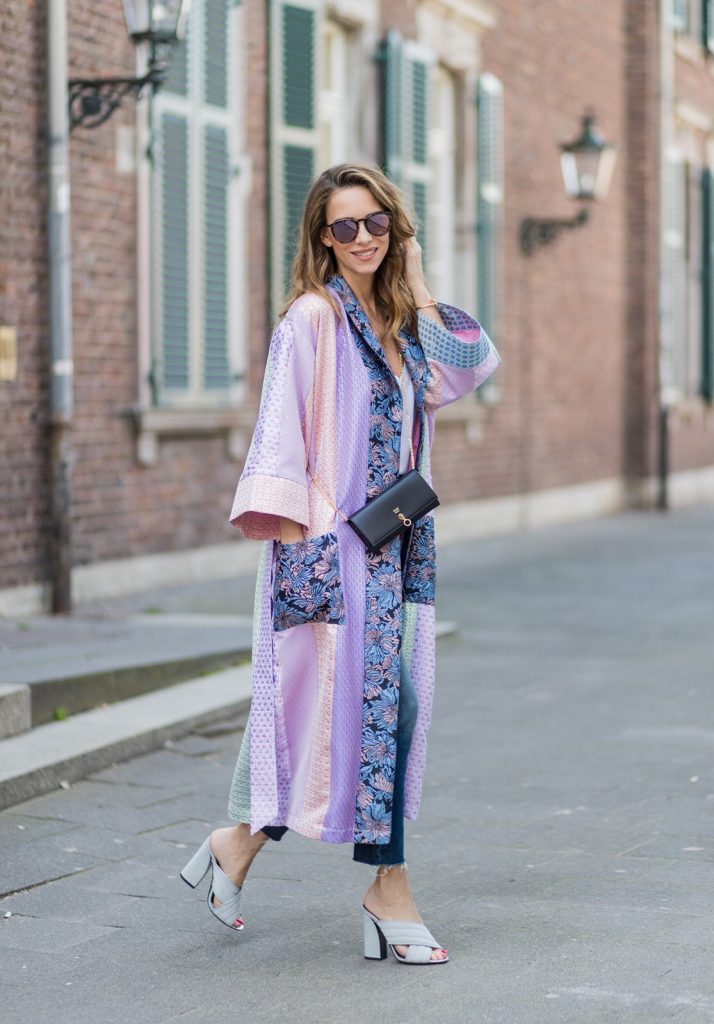 Model and fashion blogger Alexandra Lapp wearing a printed kimono / panel robe from Natasha Zinko, slim fit high waist Jeans from Rag & Bone, Mules by Gucci with open-toe-silhouette in glittery silver grey, white silk tank top from Jadicted, colorful mirrored sunglasses from Les Specs, black leather ring detail continental purse bag from Fendi featuring an embossed logo, a press stud fastening, multiple interior card slots, an interior zipped compartment and a gold-tone chain shoulder strap on March 30, 2017 in Duesseldorf, Germany.