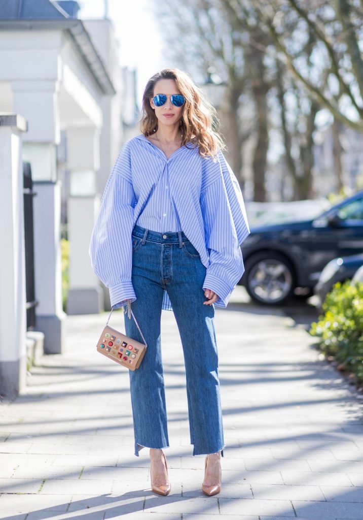 Model and fashion blogger Alexandra Lapp wearing an oversized navy and white striped cotton shirt, cut for an oversized fit with a point collar and dropped shoulders from Vetements, blue jeans from Vetements in cooperation with Levi`s with cut-out raw hems, blue aviator sunglasses from illevesta, Christian Louboutin pumps in cognac, filigree rose gold jewelry from Art Youth Society and a studded embellished crossbody bag from Fendi featuring a foldover top with magnetic closure, an interior zipped compartment, multiple interior card slots and a silver-tone chain shoulder strap on March 30, 2017 in Duesseldorf, Germany.