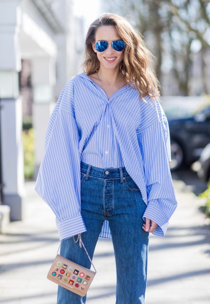 Model and fashion blogger Alexandra Lapp wearing an oversized navy and white striped cotton shirt, cut for an oversized fit with a point collar and dropped shoulders from Vetements, blue jeans from Vetements in cooperation with Levi`s with cut-out raw hems, blue aviator sunglasses from illevesta, Christian Louboutin pumps in cognac, filigree rose gold jewelry from Art Youth Society and a studded embellished crossbody bag from Fendi featuring a foldover top with magnetic closure, an interior zipped compartment, multiple interior card slots and a silver-tone chain shoulder strap on March 30, 2017 in Duesseldorf, Germany.