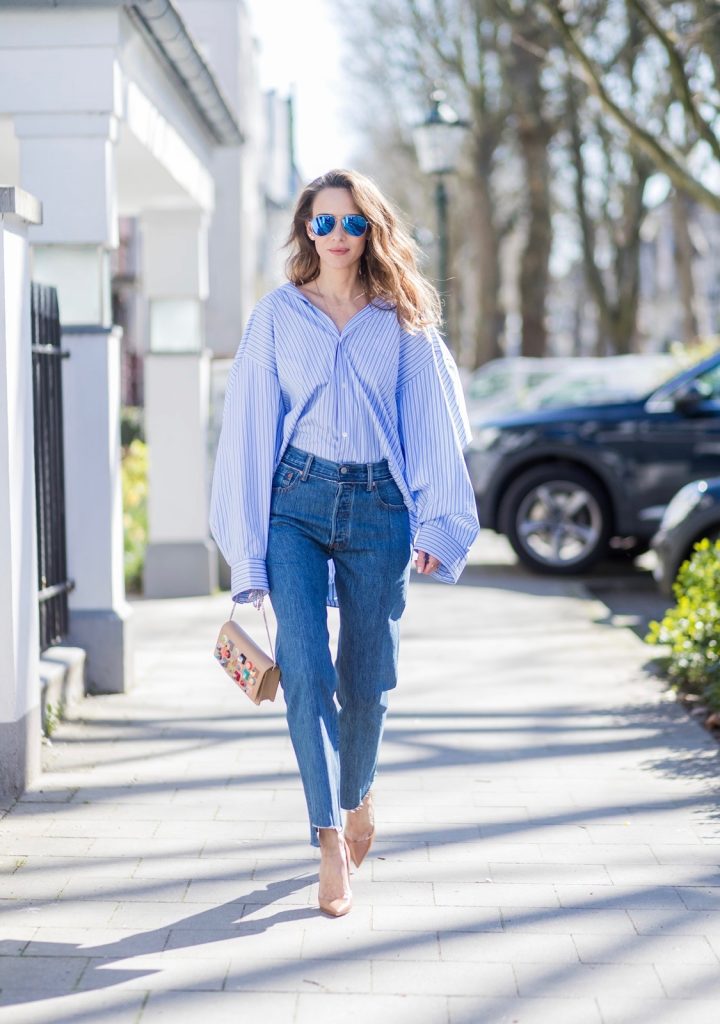 Model and fashion blogger Alexandra Lapp wearing an oversized navy and white striped cotton shirt, cut for an oversized fit with a point collar and dropped shoulders from Vetements, blue jeans from Vetements in cooperation with Levi`s with cut-out raw hems, blue aviator sunglasses from illevesta, Christian Louboutin pumps in cognac, filigree rose gold jewelry from Art Youth Society and a studded embellished crossbody bag from Fendi featuring a foldover top with magnetic closure, an interior zipped compartment, multiple interior card slots and a silver-tone chain shoulder strap on March 30, 2017 in Duesseldorf, Germany.