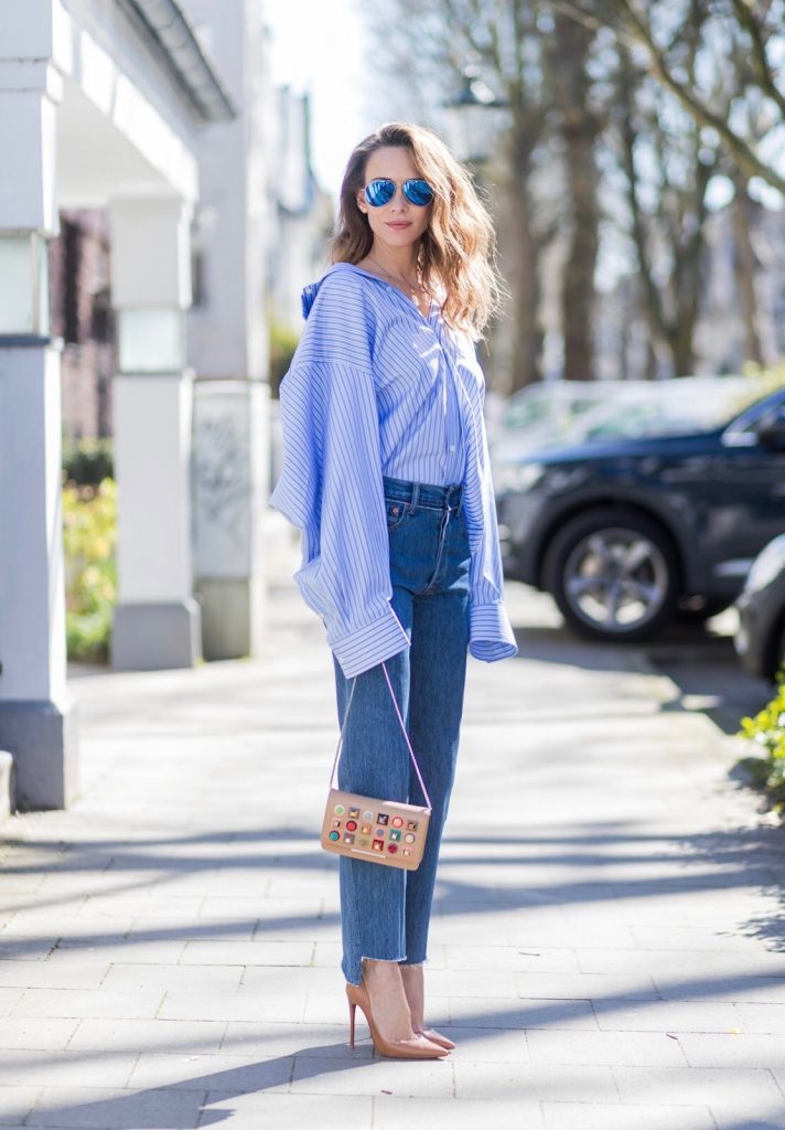 Model and fashion blogger Alexandra Lapp wearing an oversized navy and white striped cotton shirt, cut for an oversized fit with a point collar and dropped shoulders from Vetements, blue jeans from Vetements in cooperation with Levi`s with cut-out raw hems, blue aviator sunglasses from illevesta, Christian Louboutin pumps in cognac, filigree rose gold jewelry from Art Youth Society and a studded embellished crossbody bag from Fendi featuring a foldover top with magnetic closure, an interior zipped compartment, multiple interior card slots and a silver-tone chain shoulder strap on March 30, 2017 in Duesseldorf, Germany.