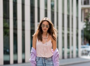 Alexandra Lapp wearing a pastel purple look, a purple cashmere cardigan by Heartbreaker, a rose tank top in silk from Jadicted, a high waist, non-strech denim, five-pocket 501 skinny jeans from Levis, a candy necklace from Chanel supermarket collection in pastel tones, a Chanel perfume bottle bag in plexiglass and a golden chain with white leather, Christian Louboutin pumps Feerica with nude mesh upper embedded with a Swarovski crystal degrade and Karl Lagerfeld cat-eye sunglasses in the shape of cat ears during the Mercedes-Benz Fashion Week Berlin Spring/Summer 2018 on July 7, 2017 in Berlin, Germany.
