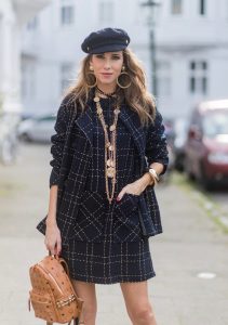 Model and fashion blogger Alexandra Lapp wearing a look inspired by Chanel, a tweed dress and coat from Steffen Schraut, Balmain x HM sandals, Strak backpack by MCM, Chanel tweed cap, golden Chanel chains in form from Chanel coins, Chanel chocker and golden bracelet from Schubart Goldschmiede and golden vintage earrings with a peals by Chanel on August 5, 2017 in Duesseldorf, Germany.