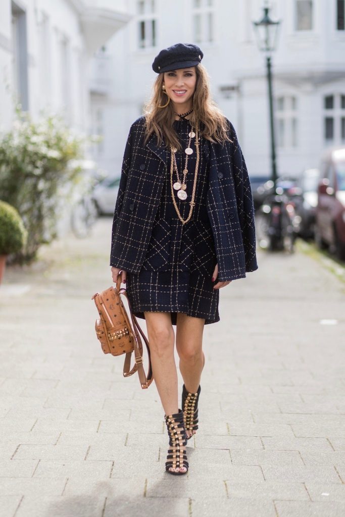 Model and fashion blogger Alexandra Lapp wearing a look inspired by Chanel, a tweed dress and coat from Steffen Schraut, Balmain x HM sandals, Strak backpack by MCM, Chanel tweed cap, golden Chanel chains in form from Chanel coins, Chanel chocker and golden bracelet from Schubart Goldschmiede and golden vintage earrings with a peals by Chanel on August 5, 2017 in Duesseldorf, Germany.