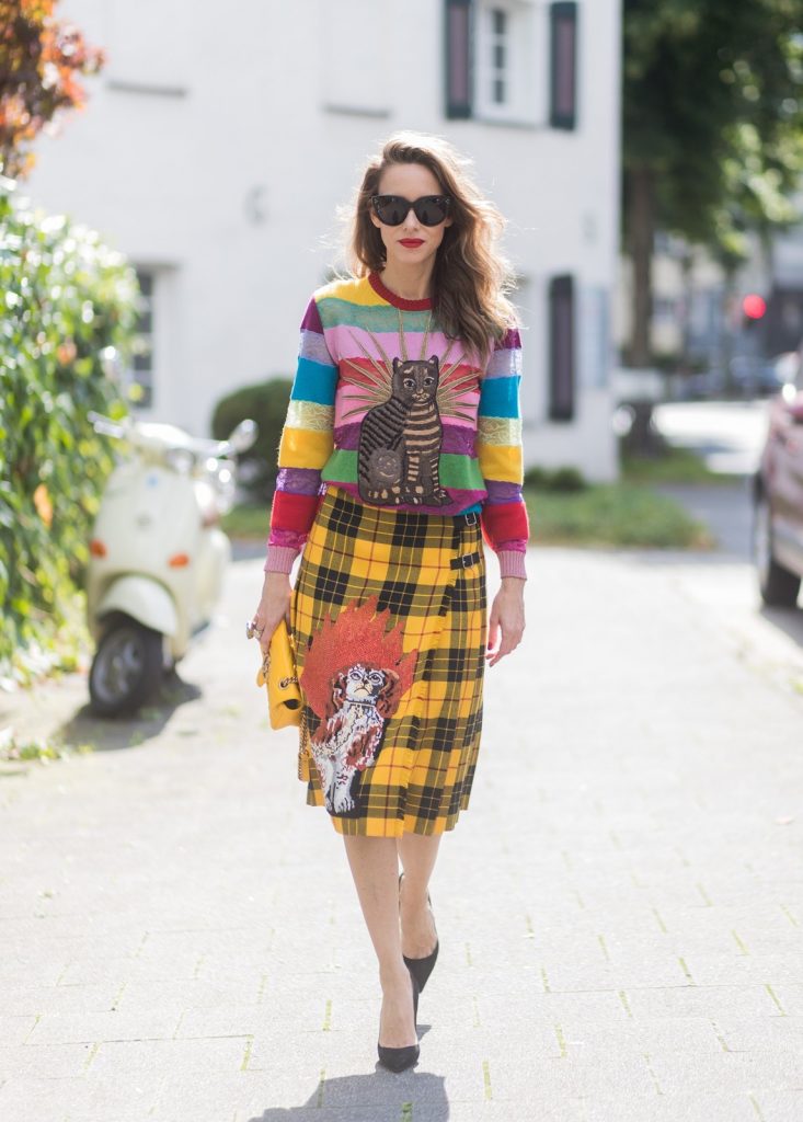 Model and Blogger Alexandra Lapp wearing a Gucci total look, yellow and red pleated tartan skirt embroidered with a spaniel dog and belt buckle closure, colorful striped sweater with lace and merino with embroidered cat applique all Gucci, black Christian Louboutin So Kate pumps, GG Marmont Gucci bag in yellow, Audrey sunglasses from Celine on August 4, 2017 in Duesseldorf, Germany.