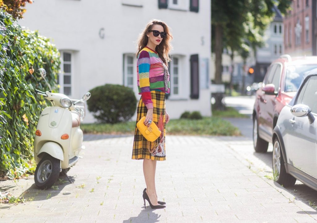 Model and Blogger Alexandra Lapp wearing a Gucci total look, yellow and red pleated tartan skirt embroidered with a spaniel dog and belt buckle closure, colorful striped sweater with lace and merino with embroidered cat applique all Gucci, black Christian Louboutin So Kate pumps, GG Marmont Gucci bag in yellow, Audrey sunglasses from Celine on August 4, 2017 in Duesseldorf, Germany.