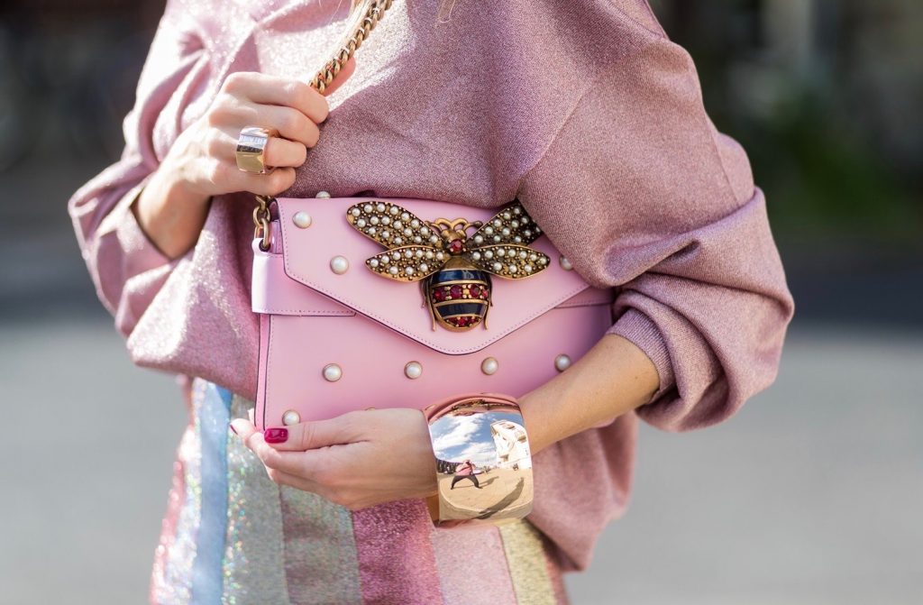 Model and fashion blogger Alexandra Lapp wearing metallic chic, pleated lame skirt in shimmering pastel, pink metallic v-neck knit by Alberta Ferretti, Christian Louboutin Feerica heels with Swarovski crystals and flower accessory, pink Broadway leather bag with pearl studs, Le Specs sunglasses, bracelet and rose gold ring with baguette diamonds by Schubart on August 4, 2017 in Duesseldorf, Germany.