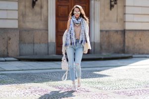Model and fashion blogger Alexandra Lapp wearing a scarf and beige cashmere cardigan by Heartbreaker, beige tank top in silk from Jadicted, a high waist, non-strech denim, five-pocket 501 skinny jeans from Levis, Roger Vivier Viv bag in leather with removable strap in trapezium shape, ankle boots from Roger Vivier in with floral cutouts and a mirrored block heel and silver mirrored sunglasses from Le Specs during the Mercedes-Benz Fashion Week Berlin Spring/Summer 2018 on July 8, 2017 in Berlin, Germany.