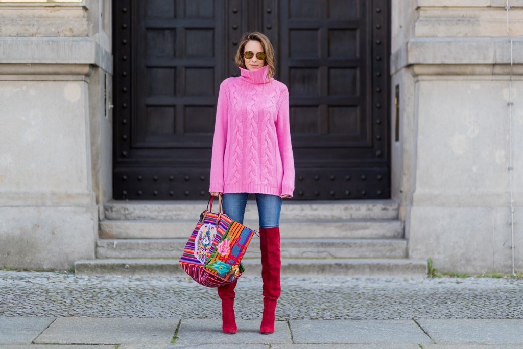 Model and fashion blogger Alexandra Lapp wearing Christian Louboutin folkloric Mexicaba tote in cotton-canvas in collaboration with the Taller Maya Foundation, a pink turtleneck in cashmere from Heartbreaker, red overknees from Gianvito Rossi, Adriano Goldschmied AG Denim Jeans and gold mirrored sunglasses by Thom Browne during the Mercedes-Benz Fashion Week Berlin Spring/Summer 2018 on July 8, 2017 in Berlin, Germany.