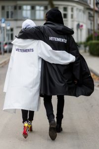 Couple look a like holding arms in front of a DHL van - Model and Blogger Alexandra Lapp wearing oversized Vetements raincoat with a hood in white, Vetements hoodie in white, destroyed Adriano Goldschmied high waist denim in black, black and white So Kate pumps with a yellow heel, yellow golden lacquer Boy bag from Chanel and a big golden ring with baguette diamonds from Schubart Goldschmiede and Model and Blogger Thomas Stuch wearing black oversized raincoat with a hood in black from Vetements, Stella McCartney hoodie in black, Dsquared slim fit denim, Ghost cowboy boots on August 4, 2017 in Duesseldorf, Germany.