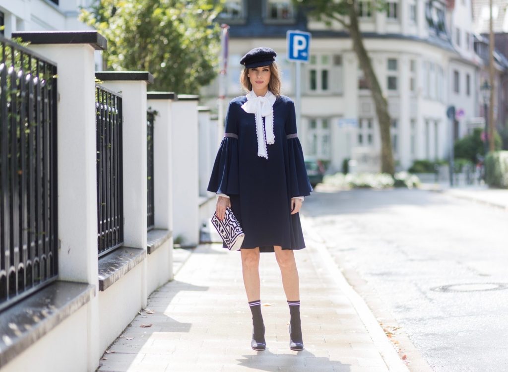 Model and fashion blogger Alexandra Lapp wearing a navy dress with oversized sleeves and a white tie-neck blouse from Steffen Schraut, Chanel tweed cap, baroque Fendi sock-boots in black and white, Chanel 2.55 classic back in white leather with black pearls on August 4, 2017 in Duesseldorf, Germany. 
