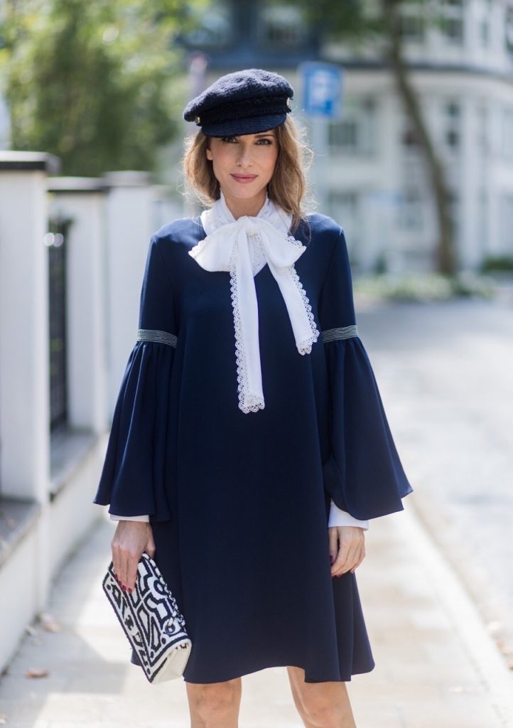 Model and fashion blogger Alexandra Lapp wearing a navy dress with oversized sleeves and a white tie-neck blouse from Steffen Schraut, Chanel tweed cap, baroque Fendi sock-boots in black and white, Chanel 2.55 classic back in white leather with black pearls on August 4, 2017 in Duesseldorf, Germany. 