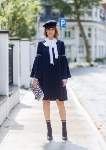Model and fashion blogger Alexandra Lapp wearing a navy dress with oversized sleeves and a white tie-neck blouse from Steffen Schraut, Chanel tweed cap, baroque Fendi sock-boots in black and white, Chanel 2.55 classic back in white leather with black pearls on August 4, 2017 in Duesseldorf, Germany.