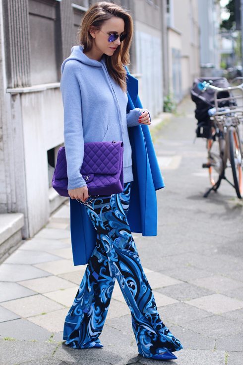 Alexandra Lapp wearing a light blue cashmere hoodie by Heartbreaker, colorful pants in all tones of blue from Emilio Pucci, a blue cashmere coat by Jil Sander, an oversized purple 2.55 tweed bag from Chanel, purple aviator sunglasses from Ray Ban, Gianvito Rossi heels.