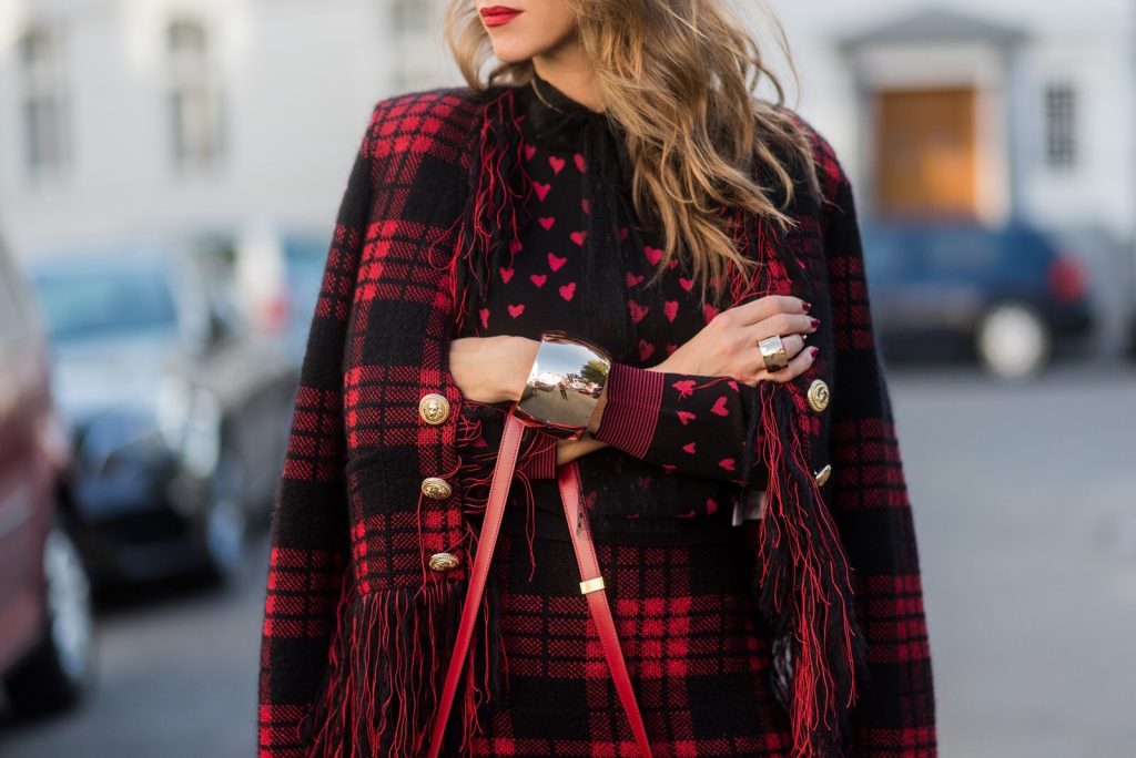 Model and fashion blogger Alexandra Lapp wearing a military jacket in red and black with checkered pattern and frayed sleeves from Balmain, plaid pattern high waist mini skirt by Balmain, red heart intarsia knit by Red Valentino, Celine Box bag in red and red lacquer pumps by Gianvito Rossi, rose gold ring with baguette diamonds on August 4, 2017 in Duesseldorf, Germany.