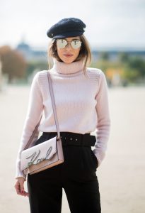 Alexandra Lapp wearing high waist pants in black from Zara, cashmere turtleneck in light pink from Jil Sander, light pink calf leather logo plaque shoulder bag from Karl Lagerfeld, Karl Lagerfeld bag, mirrored sunglasses by Le Specs, hat by Chanel, IWC Portugieser watch and Christian Louboutin Feerica heels with crystal embellished flower and glitter is seen during Paris Fashion Week Spring/Summer 2018 on September 29, 2017 in Paris, France.