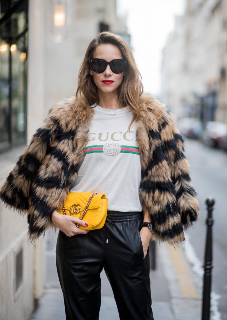 Alexandra Lapp wearing leather trackies in black from Set Fashion, vintage style Gucci logo tee, little fur jacket by Set, yellow GG Marmont matelasse shoulder bag by Gucci, red lacquer heels from Gianvito Rossi and Audrey sunglasses from Celine is seen during Paris Fashion Week Spring/Summer 2018 on September 27, 2017 in Paris, France.