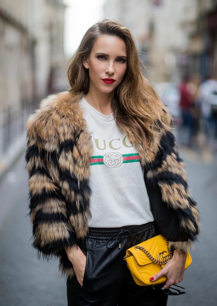 Alexandra Lapp wearing leather trackies in black from Set Fashion, vintage style Gucci logo tee, little fur jacket by Set, yellow GG Marmont matelasse shoulder bag by Gucci, red lacquer heels from Gianvito Rossi and Audrey sunglasses from Celine is seen during Paris Fashion Week Spring/Summer 2018 on September 27, 2017 in Paris, France.