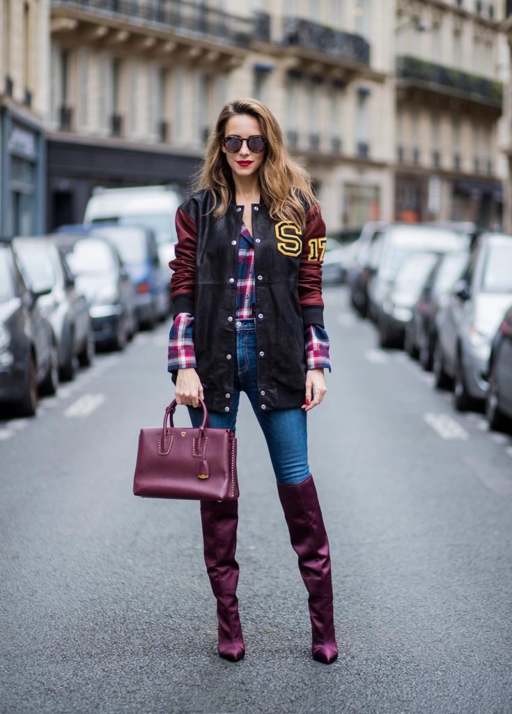 Alexandra Lapp wearing an oversized college jacket in leather from Set Fashion, a plaid shirt with studs from Set, high waist skinny jeans by Rag and Bone, Milla Tote bag with studded outlines in rustic brown from MCM, Les Specs sunglasses, and overknee boots in burgundy by Zara is seen during Paris Fashion Week Spring/Summer 2018 on September 26, 2017 in Paris, France.