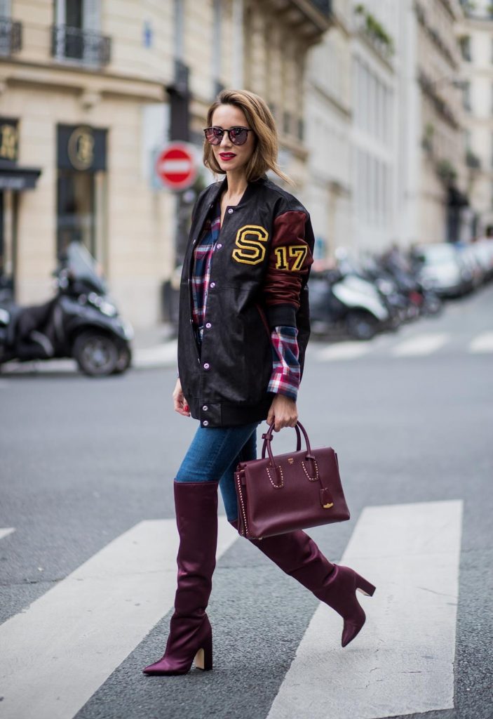 Alexandra Lapp wearing an oversized college jacket in leather from Set Fashion, a plaid shirt with studs from Set, high waist skinny jeans by Rag and Bone, Milla Tote bag with studded outlines in rustic brown from MCM, Les Specs sunglasses, and overknee boots in burgundy by Zara is seen during Paris Fashion Week Spring/Summer 2018 on September 26, 2017 in Paris, France.