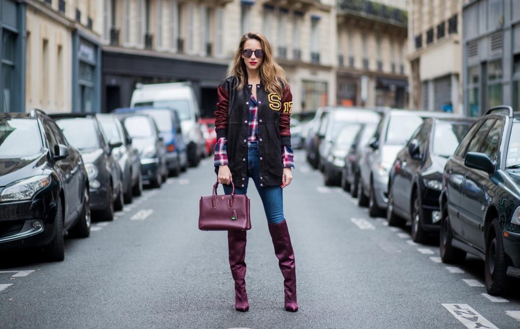 Alexandra Lapp wearing an oversized college jacket in leather from Set Fashion, a plaid shirt with studs from Set, high waist skinny jeans by Rag and Bone, Milla Tote bag with studded outlines in rustic brown from MCM, Les Specs sunglasses, and overknee boots in burgundy by Zara is seen during Paris Fashion Week Spring/Summer 2018 on September 26, 2017 in Paris, France.