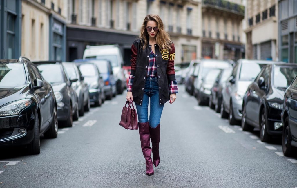 Alexandra Lapp wearing an oversized college jacket in leather from Set Fashion, a plaid shirt with studs from Set, high waist skinny jeans by Rag and Bone, Milla Tote bag with studded outlines in rustic brown from MCM, Les Specs sunglasses, and overknee boots in burgundy by Zara is seen during Paris Fashion Week Spring/Summer 2018 on September 26, 2017 in Paris, France.