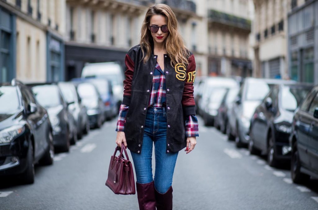 Alexandra Lapp wearing an oversized college jacket in leather from Set Fashion, a plaid shirt with studs from Set, high waist skinny jeans by Rag and Bone, Milla Tote bag with studded outlines in rustic brown from MCM, Les Specs sunglasses, and overknee boots in burgundy by Zara is seen during Paris Fashion Week Spring/Summer 2018 on September 26, 2017 in Paris, France.