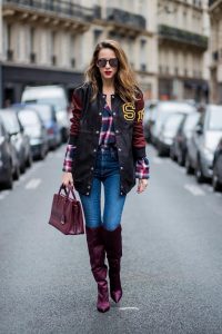 Alexandra Lapp wearing an oversized college jacket in leather from Set Fashion, a plaid shirt with studs from Set, high waist skinny jeans by Rag and Bone, Milla Tote bag with studded outlines in rustic brown from MCM, Les Specs sunglasses, and overknee boots in burgundy by Zara is seen during Paris Fashion Week Spring/Summer 2018 on September 26, 2017 in Paris, France.