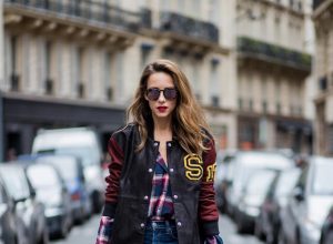 Alexandra Lapp wearing an oversized college jacket in leather from Set Fashion, a plaid shirt with studs from Set, high waist skinny jeans by Rag and Bone, Milla Tote bag with studded outlines in rustic brown from MCM, Les Specs sunglasses, and overknee boots in burgundy by Zara is seen during Paris Fashion Week Spring/Summer 2018 on September 26, 2017 in Paris, France.