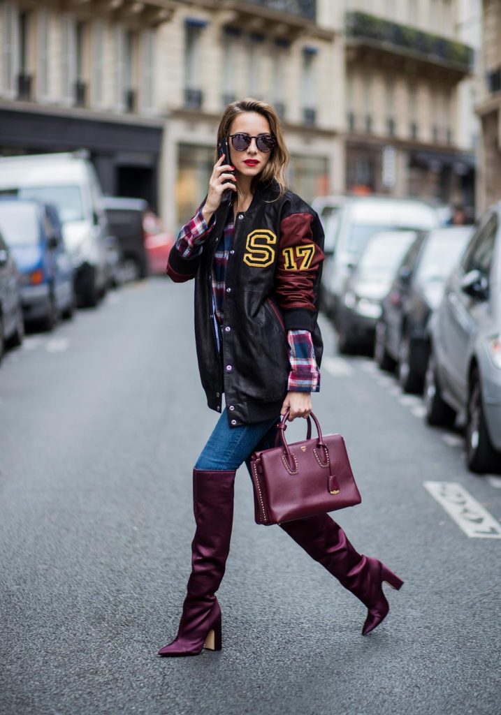 Alexandra Lapp wearing an oversized college jacket in leather from Set Fashion, a plaid shirt with studs from Set, high waist skinny jeans by Rag and Bone, Milla Tote bag with studded outlines in rustic brown from MCM, Les Specs sunglasses, and overknee boots in burgundy by Zara is seen during Paris Fashion Week Spring/Summer 2018 on September 26, 2017 in Paris, France.