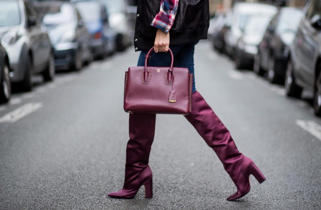 Alexandra Lapp wearing an oversized college jacket in leather from Set Fashion, a plaid shirt with studs from Set, high waist skinny jeans by Rag and Bone, Milla Tote bag with studded outlines in rustic brown from MCM, Les Specs sunglasses, and overknee boots in burgundy by Zara is seen during Paris Fashion Week Spring/Summer 2018 on September 26, 2017 in Paris, France.