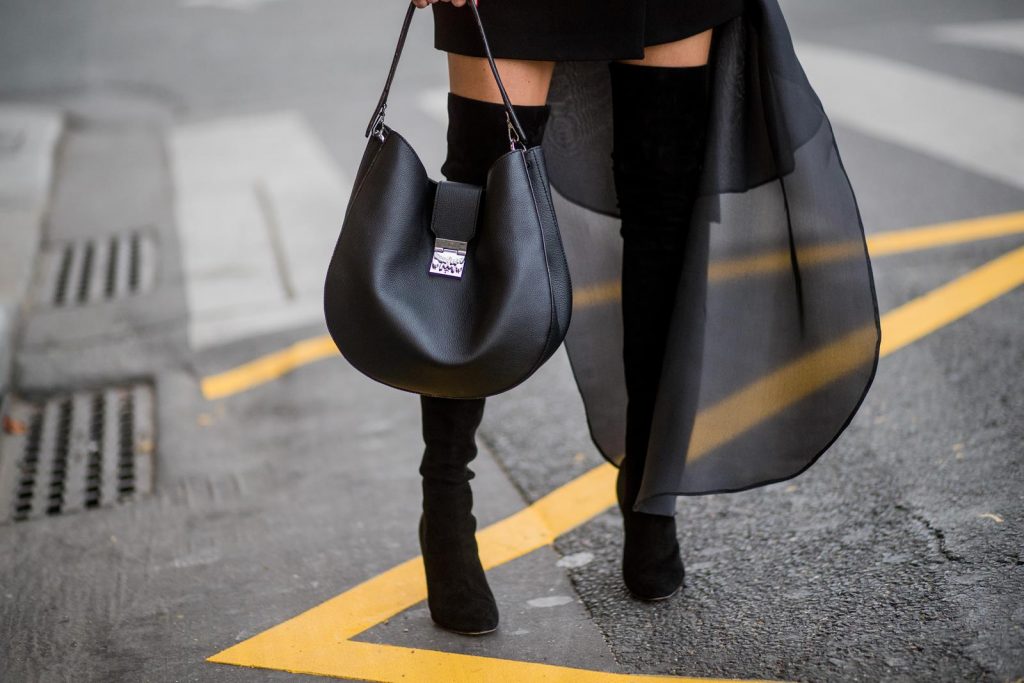 Alexandra Lapp wearing a Tuxedo Dress with detachable overlay in black from Pearl and Rubies, collier de chien waist belt by Hermes, black overknee boots from Gianvito Rossi, hat by Chanel and Patricia Hobo bag with a rounded shape and a Laurel Lock closure seen during Paris Fashion Week Spring/Summer 2018 on October 2, 2017 in Paris, France.