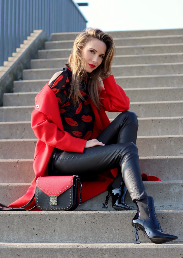 Alexandra Lapp wearing the new MCM Made-To-Order Patricia bag, a Made-To-Order service, giving everyone the opportunity of designing her own personal and unique Patricia bag, black leather pants from Unravel, a silk blouse with red lips from Saint Laurent, a cashmere coat in red from Hermès, black patent ankle boots from YSL, red lipstick by Dior.