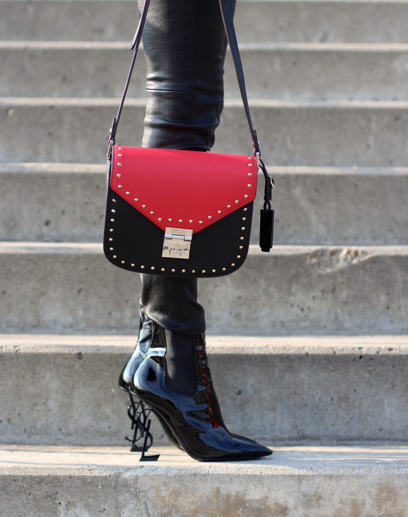 Alexandra Lapp wearing the new MCM Made-To-Order Patricia bag, a Made-To-Order service, giving everyone the opportunity of designing her own personal and unique Patricia bag, black leather pants from Unravel, a silk blouse with red lips from Saint Laurent, a cashmere coat in red from Hermès, black patent ankle boots from YSL, red lipstick by Dior.