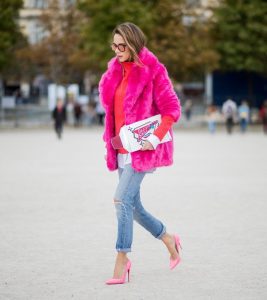 Alexandra Lapp wearing a fake fur jacket in pink from Jakke with a Faux Real statement on the back, red cashmere jumper by Heartbreaker with golden buttons, a long white blouse by Celine, Levis ReDone denim, Christian Louboutin heels in neon pink, sunglasses by Le Specs and a clutch by Yazburkey with a Dazzlin Smile application is seen during Paris Fashion Week Spring/Summer 2018 on September 27, 2017 in Paris, France.