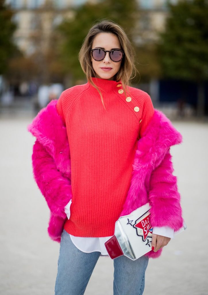 Alexandra Lapp wearing a fake fur jacket in pink from Jakke with a Faux Real statement on the back, red cashmere jumper by Heartbreaker with golden buttons, a long white blouse by Celine, Levis ReDone denim, Christian Louboutin heels in neon pink, sunglasses by Le Specs and a clutch by Yazburkey with a Dazzlin Smile application is seen during Paris Fashion Week Spring/Summer 2018 on September 27, 2017 in Paris, France.