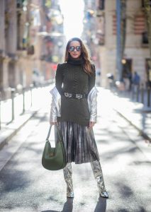 Alexandra Lapp wearing metallic look, a pleated skirt in a washed out silver metallic and black style, long knitted dark green Celine turtle neck pullover with cable stitch, black waist belt from Hermes with heavy silver buckle and silver stud details, short cut silver leather jacket with zippers from Set Fashion, silver metallic boots from H&M, large green Patricia Hobo bag from MCM and sunglasses from Le Specs on November 28, 2017 in Barcelona, Spain.