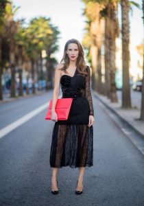 Alexandra Lapp wearing a little black dress, asymmetric shoulder dress with a delicate floral lace and a velvet fitted bustier from Three Floor, Pigalle Christian Louboutin black patent leather heels and a simple MCM pouch in marigold orange on November 29, 2017 in Barcelona, Spain.