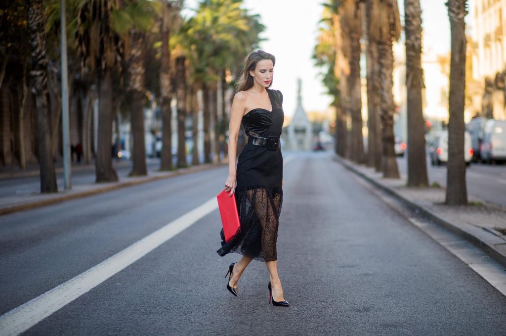 Alexandra Lapp wearing a little black dress, asymmetric shoulder dress with a delicate floral lace and a velvet fitted bustier from Three Floor, Pigalle Christian Louboutin black patent leather heels and a simple MCM pouch in marigold orange on November 29, 2017 in Barcelona, Spain.