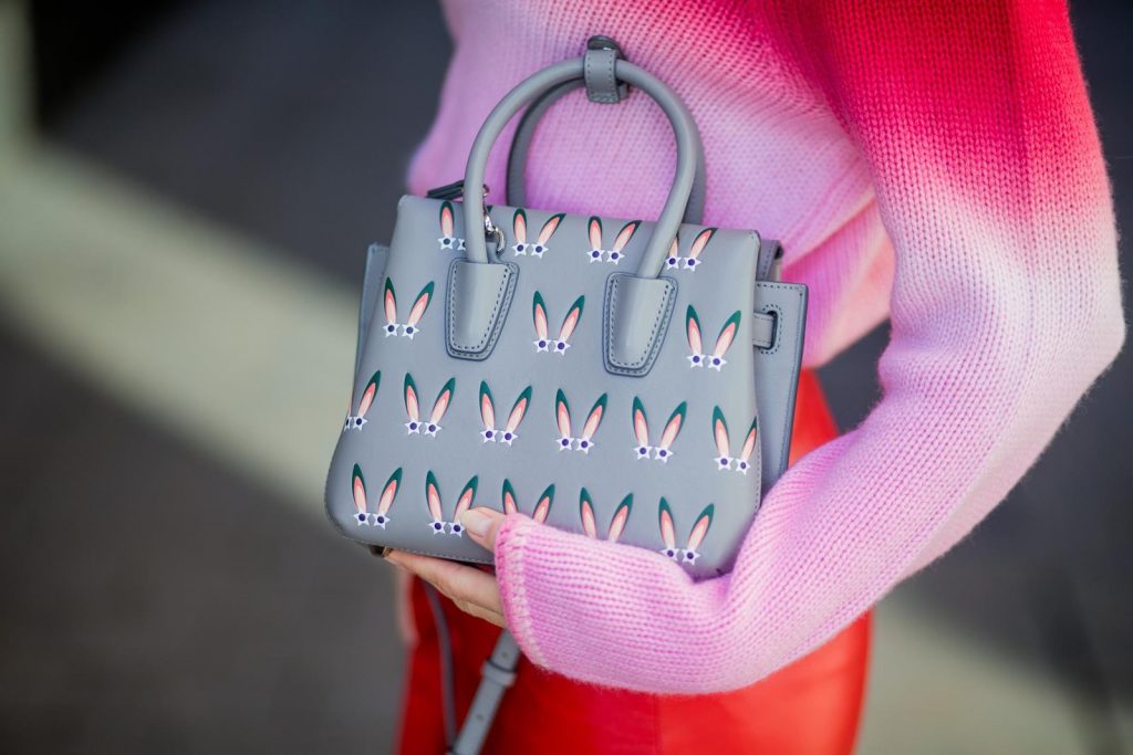 Alexandra Lapp wearing batik knit, a red leather mini skirt with integrated belt around the waist from Set Fashion, a batik cashmere pullover in pink and red from Heartbreaker, red satin pumps from Christian Louboutin with long satin bow, silver shadow colored MCM Milla Tote bag on November 27, 2017 in Barcelona, Spain.